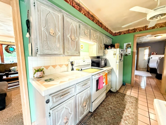 6424 W Farm Rd Unit 140, Springfield, MO 65802 - kitchen with white appliances, tile countertops, decorative backsplash, a ceiling fan, and light tile patterned floors