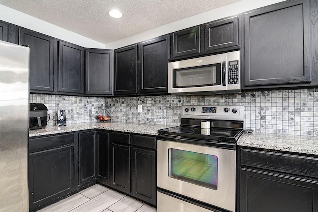 828 S Chinkapin Ave, Nixa, MO 65714 - kitchen with stainless steel appliances, dark cabinets, backsplash, and a textured ceiling