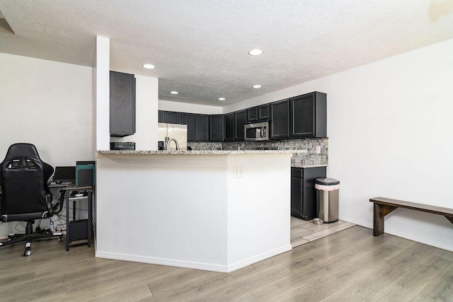 828 S Chinkapin Ave, Nixa, MO 65714 - kitchen featuring appliances with stainless steel finishes, light wood-style floors, light stone counters, backsplash, and an office area