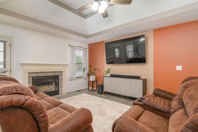 828 S Chinkapin Ave, Nixa, MO 65714 - living area featuring a stone fireplace, wood finished floors, a ceiling fan, and a tray ceiling