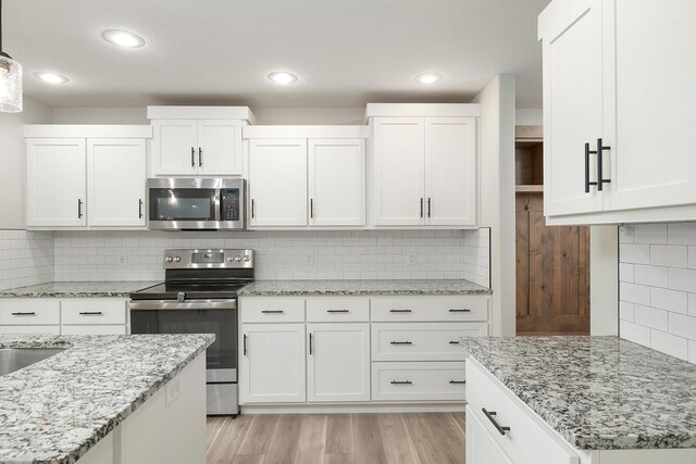 2801 E Bradford St, Republic, MO 65738 - kitchen featuring appliances with stainless steel finishes, light wood-style floors, white cabinetry, tasteful backsplash, and light stone counters