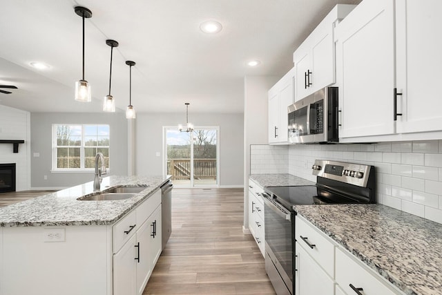 2801 E Bradford St, Republic, MO 65738 - kitchen with appliances with stainless steel finishes, a fireplace, light wood-style floors, open floor plan, and decorative backsplash