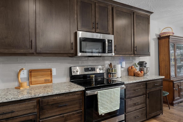 2060 Buckhorn Rd, Ozark, MO 65721 - kitchen featuring stainless steel appliances, dark brown cabinetry, decorative backsplash, light stone countertops, and light wood-style flooring