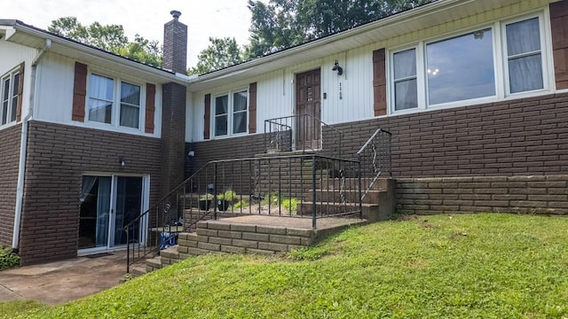 1160 Bethel Ave, Mammoth Spring, AR 72554 - property entrance with a chimney, brick siding, a lawn, and a patio