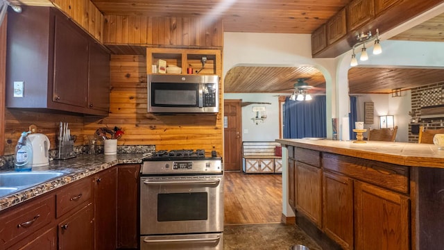 1160 Bethel Ave, Mammoth Spring, AR 72554 - kitchen featuring appliances with stainless steel finishes, wood ceiling, ceiling fan, and wood walls