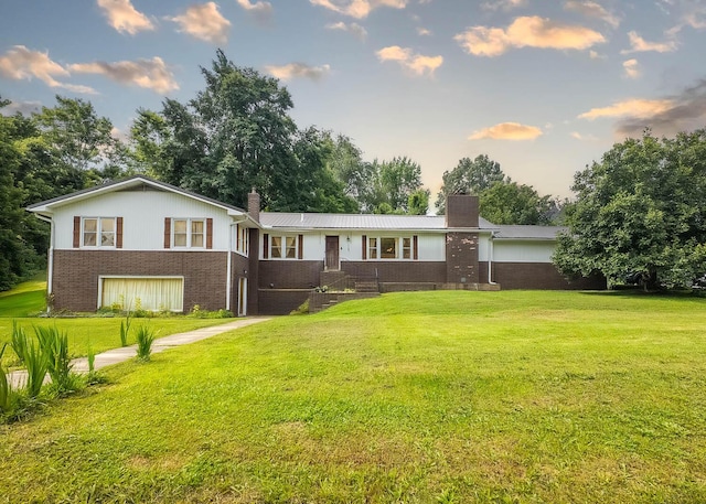 1160 Bethel Ave, Mammoth Spring, AR 72554 - back of house at dusk with a chimney, brick siding, and a lawn