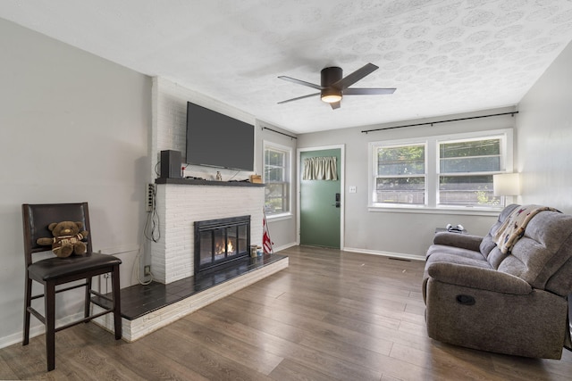 1547 S Kickapoo Ave, Springfield, MO 65804 - living area with ceiling fan, a fireplace, wood finished floors, and a textured ceiling