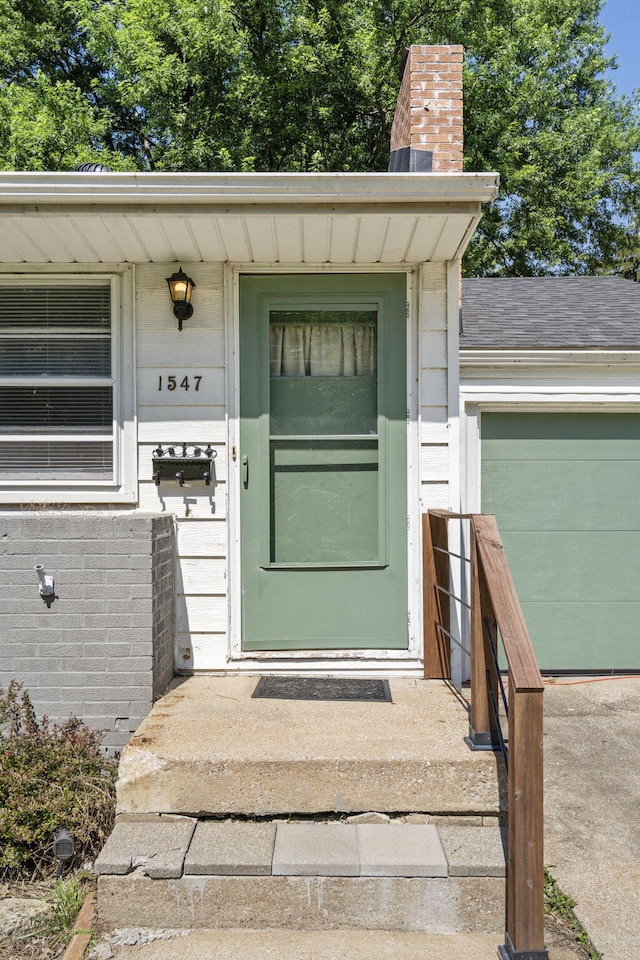 1547 S Kickapoo Ave, Springfield, MO 65804 - view of exterior entry with a chimney, an attached garage, and brick siding