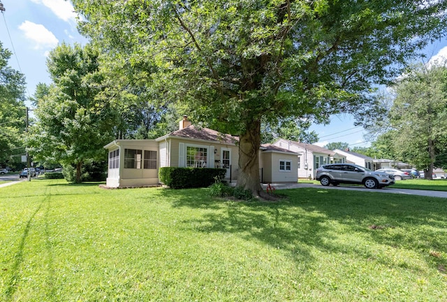 220 E Portland St, Springfield, MO 65807 - view of front of house featuring a chimney, a front yard, and a sunroom