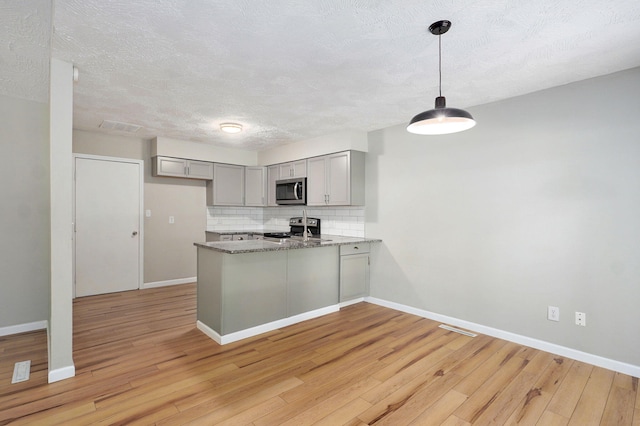 3656 S Kansas Ave, Springfield, MO 65807 - kitchen featuring stainless steel appliances, gray cabinetry, a peninsula, light wood-type flooring, and tasteful backsplash