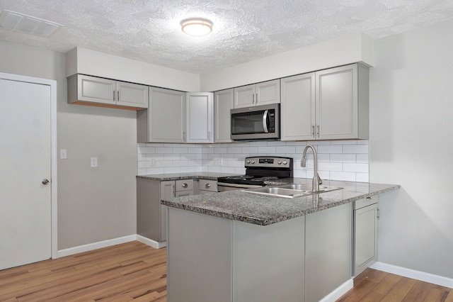 3656 S Kansas Ave, Springfield, MO 65807 - kitchen featuring appliances with stainless steel finishes, gray cabinets, light wood finished floors, a peninsula, and a textured ceiling