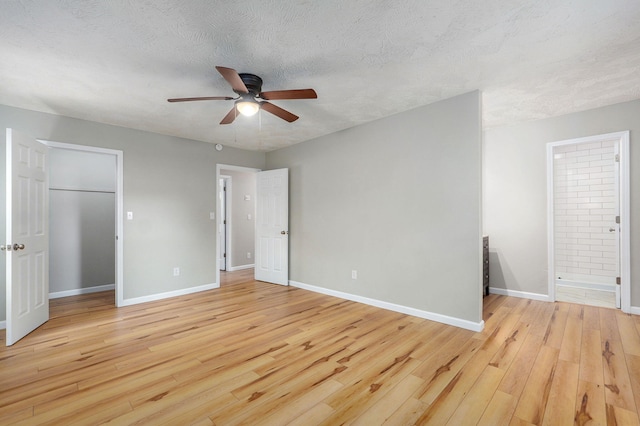 3656 S Kansas Ave, Springfield, MO 65807 - unfurnished bedroom featuring light wood finished floors, a textured ceiling, ensuite bathroom, a walk in closet, and a ceiling fan