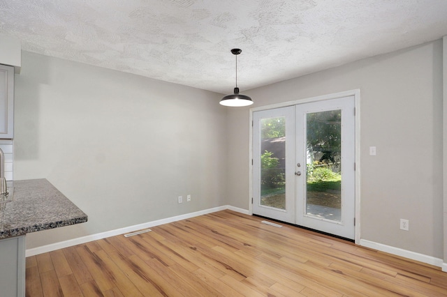 3656 S Kansas Ave, Springfield, MO 65807 - unfurnished dining area with light wood finished floors, french doors, and a textured ceiling
