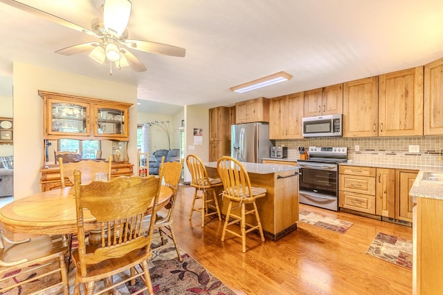 10675 State Highway Aa, Grovespring, MO 65662 - kitchen featuring appliances with stainless steel finishes, light wood-type flooring, backsplash, and ceiling fan