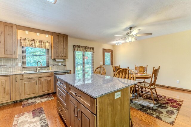 10675 State Highway Aa, Grovespring, MO 65662 - kitchen with light wood-style flooring, backsplash, a center island, stainless steel dishwasher, and light stone counters