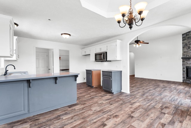 639 N Althea Ave, Nixa, MO 65714 - kitchen with arched walkways, stainless steel microwave, a ceiling fan, wood finished floors, and white cabinetry