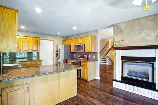 4939 S Prairie View Ave, Battlefield, MO 65619 - kitchen with stainless steel appliances, dark wood-style floors, dark stone counters, a peninsula, and decorative backsplash