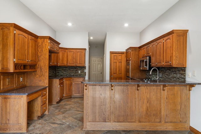 2661 E Ridgewood Dr, Springfield, MO 65804 - kitchen with stainless steel microwave, a peninsula, backsplash, dark stone countertops, and dark stone finish flooring