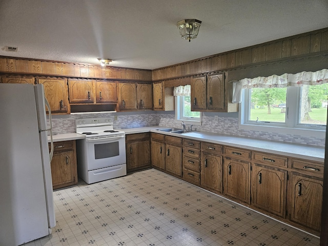 1713 Wall Rd, Mountain Grove, MO 65711 - kitchen featuring white appliances, range hood, light floors, brown cabinetry, and decorative backsplash