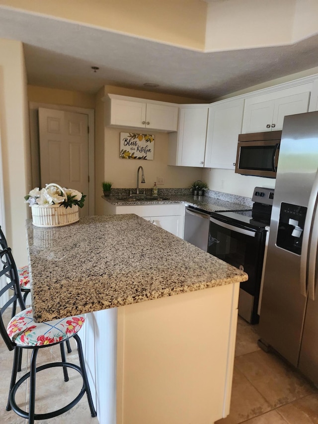 180 Grace Chapel Rd Unit 228, Blue Eye, MO 65611 - kitchen with appliances with stainless steel finishes, white cabinetry, light stone countertops, light tile patterned flooring, and a kitchen island