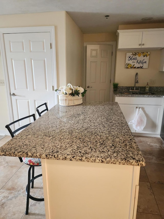 180 Grace Chapel Rd Unit 228, Blue Eye, MO 65611 - kitchen with light stone counters, white cabinets, a kitchen island, and a kitchen bar