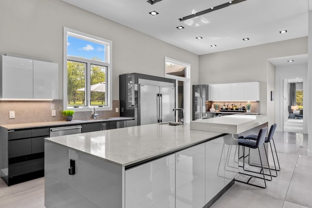 6298 E Summit View Dr, Springfield, MO 65809 - kitchen with modern cabinets, stainless steel built in fridge, white cabinetry, tasteful backsplash, and light stone countertops