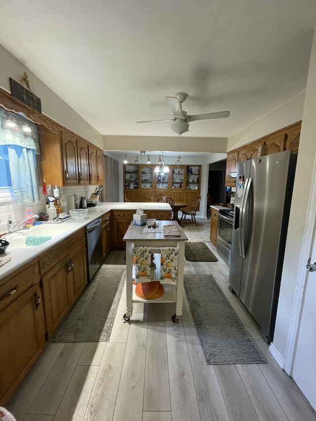 2105 Oakridge Dr, Ava, MO 65608 - kitchen featuring appliances with stainless steel finishes, a peninsula, light countertops, light wood-type flooring, and brown cabinetry