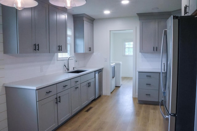 325 N Delaware Ave, Nixa, MO 65714 - kitchen featuring stainless steel appliances, washer and dryer, light wood-style floors, gray cabinets, and light countertops