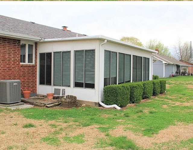 1301 W Blair Dr, Stockton, MO 65785 - view of property exterior featuring a lawn, a shingled roof, brick siding, and a sunroom