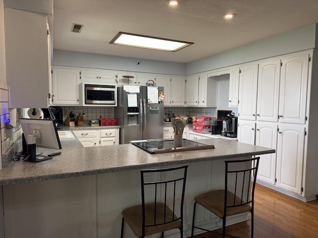 1301 W Blair Dr, Stockton, MO 65785 - kitchen featuring appliances with stainless steel finishes, a peninsula, backsplash, white cabinetry, and recessed lighting