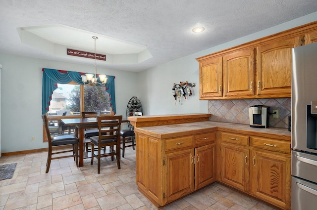 5150 S Dollison Ave, Springfield, MO 65810 - kitchen with stainless steel refrigerator with ice dispenser, tile counters, a tray ceiling, tasteful backsplash, and a textured ceiling