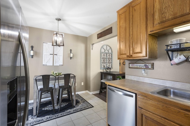 151 Vixen Cir Unit L, Branson, MO 65616 - kitchen with stainless steel appliances, brown cabinetry, light tile patterned floors, a chandelier, and pendant lighting