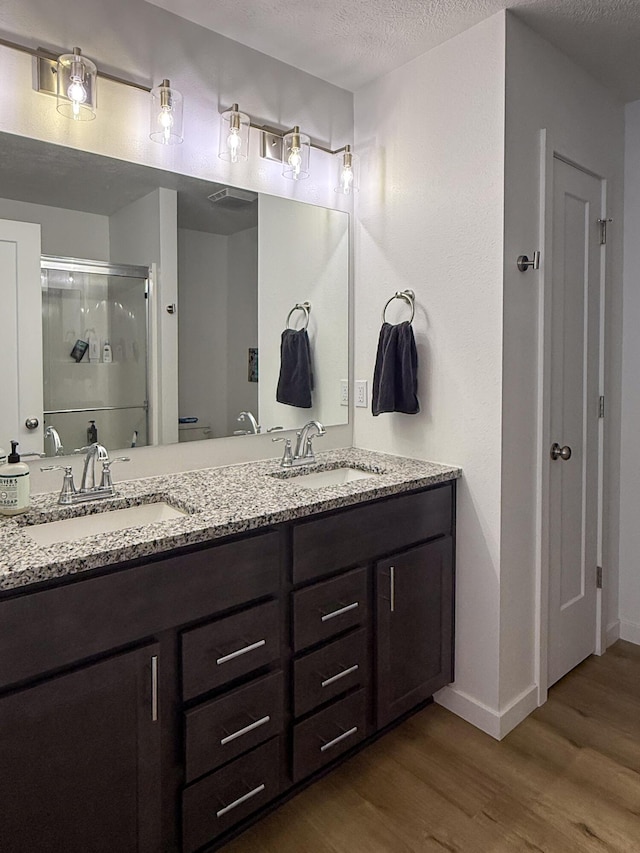 404 N Pine Leaf Rd, Nixa, MO 65714 - bathroom featuring wood finished floors, a stall shower, double vanity, and a textured ceiling