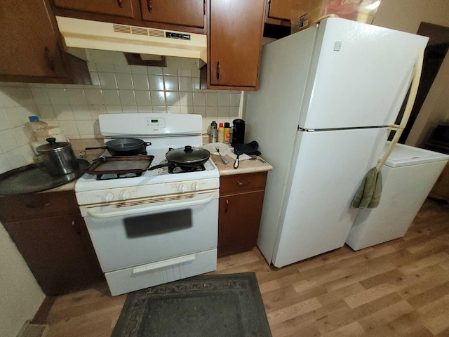 311 W Pine St, El Dorado Springs, MO 64744 - kitchen with white appliances, under cabinet range hood, tasteful backsplash, and light wood-type flooring