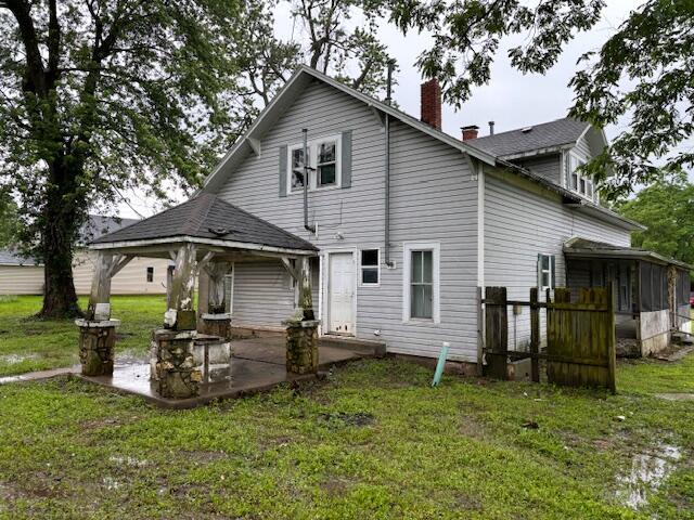 148 E Front St, Fordland, MO 65652 - back of house featuring a chimney, a patio area, a sunroom, and a lawn