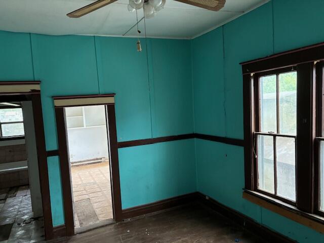 148 E Front St, Fordland, MO 65652 - empty room featuring a ceiling fan, a decorative wall, a baseboard radiator, and dark wood-type flooring