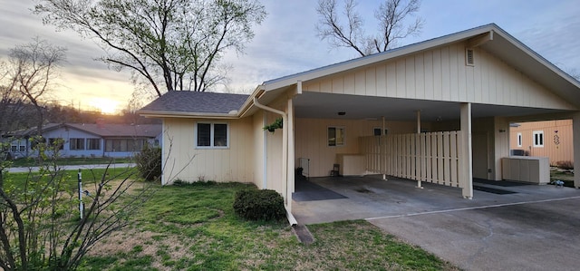16 Magnolia Ct Unit B, Branson, MO 65616 - back of property at dusk featuring driveway, an attached carport, roof with shingles, and a lawn