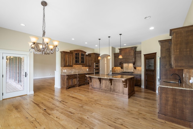 755 N Fallbrooke Ter, Springfield, MO 65802 - kitchen with a kitchen island with sink, decorative backsplash, arched walkways, a breakfast bar area, and recessed lighting