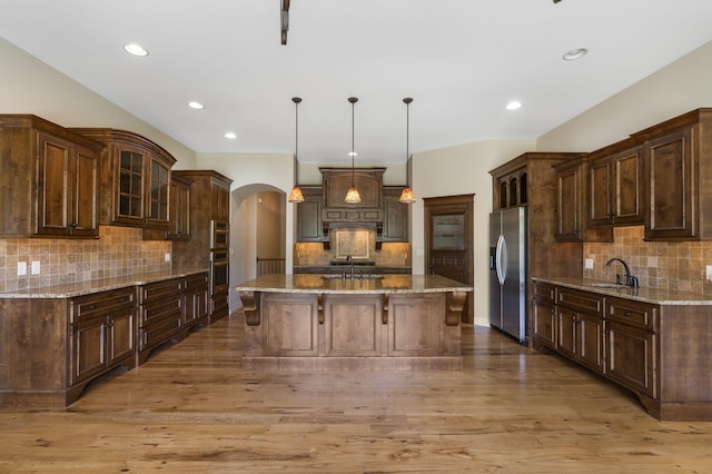 755 N Fallbrooke Ter, Springfield, MO 65802 - kitchen featuring decorative backsplash, stainless steel appliances, arched walkways, a center island, and a breakfast bar