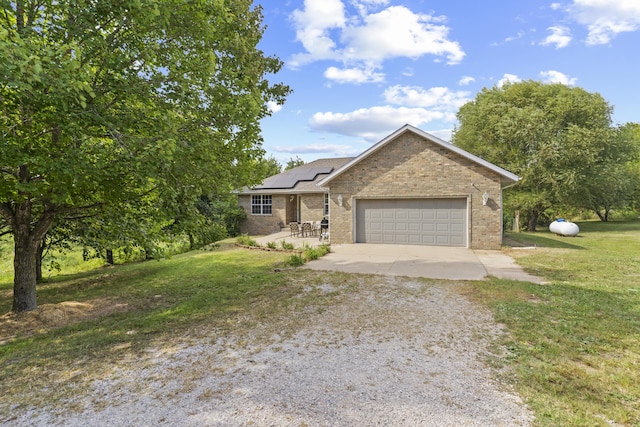 1917 Willoughby Rd, Clever, MO 65631 - view of front facade featuring driveway, roof mounted solar panels, a garage, brick siding, and a front yard