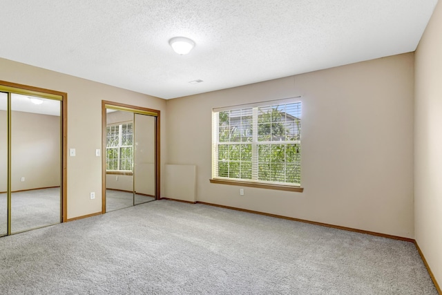 5590 S Aaron Ave, Springfield, MO 65810 - unfurnished bedroom featuring two closets, carpet, multiple windows, and a textured ceiling