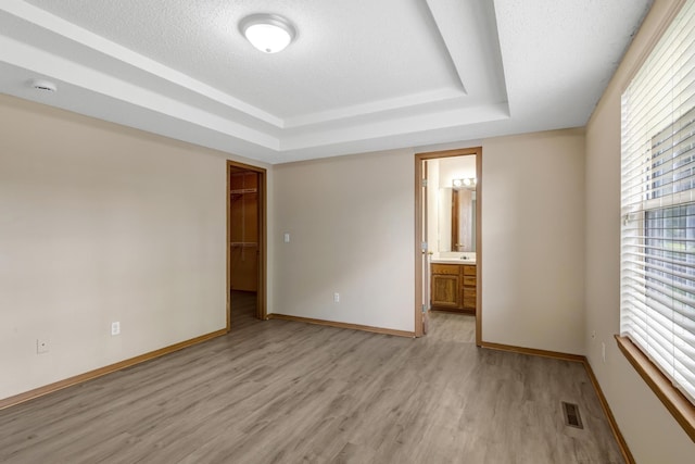 5590 S Aaron Ave, Springfield, MO 65810 - unfurnished bedroom featuring light wood finished floors, a raised ceiling, a closet, and a walk in closet