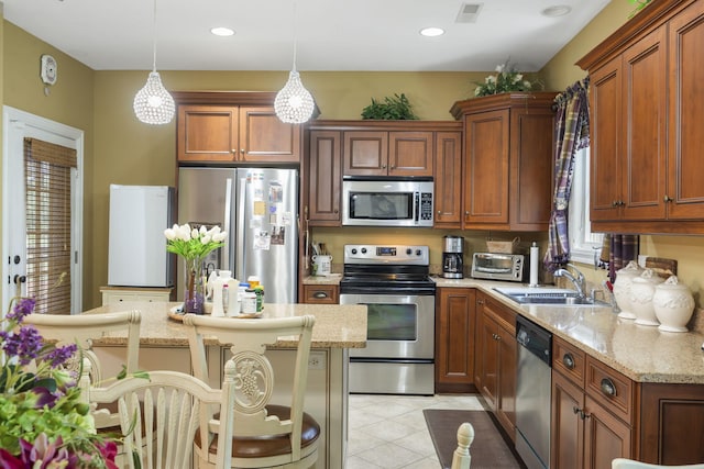 110 Stillwood Dr, Branson, MO 65616 - kitchen with stainless steel appliances, decorative light fixtures, light tile patterned flooring, light stone counters, and brown cabinets