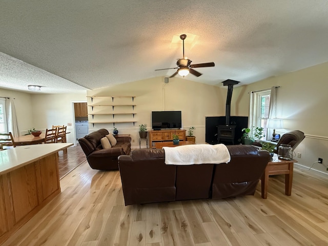 16051 Mo 142, Thayer, MO 65791 - living area with a wood stove, a textured ceiling, light wood-type flooring, a ceiling fan, and lofted ceiling