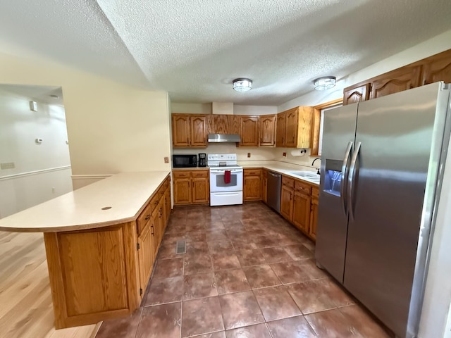 16051 Mo 142, Thayer, MO 65791 - kitchen featuring stainless steel appliances, a peninsula, under cabinet range hood, light countertops, and brown cabinetry