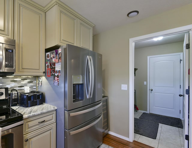 440 Spring Meadow Pkwy, Branson, MO 65616 - kitchen featuring cream cabinets, appliances with stainless steel finishes, decorative backsplash, and light tile patterned floors