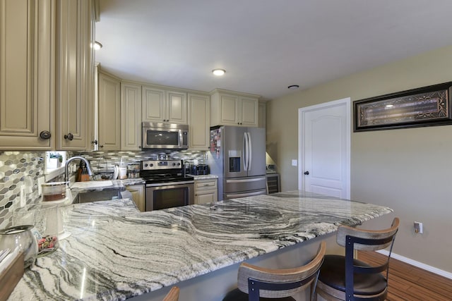 440 Spring Meadow Pkwy, Branson, MO 65616 - kitchen featuring cream cabinets, stainless steel appliances, decorative backsplash, light stone countertops, and dark wood-style flooring