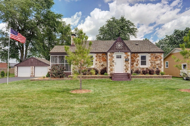 1841 E Dale St, Springfield, MO 65803 - tudor-style house featuring stone siding, a detached garage, an outbuilding, a shingled roof, and a front lawn