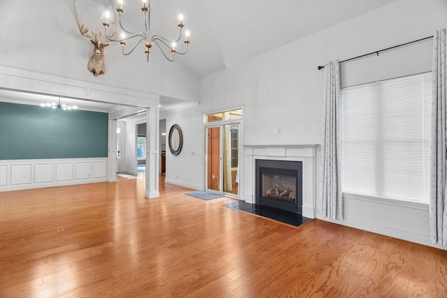 253 Cedar Glade Dr, Branson West, MO 65737 - unfurnished living room with a chandelier, wood finished floors, a tiled fireplace, high vaulted ceiling, and a decorative wall
