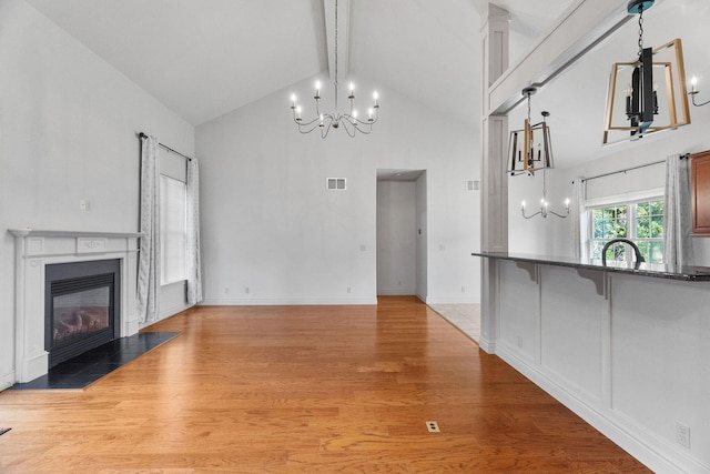253 Cedar Glade Dr, Branson West, MO 65737 - unfurnished living room featuring a chandelier, high vaulted ceiling, beam ceiling, a fireplace with flush hearth, and light wood finished floors